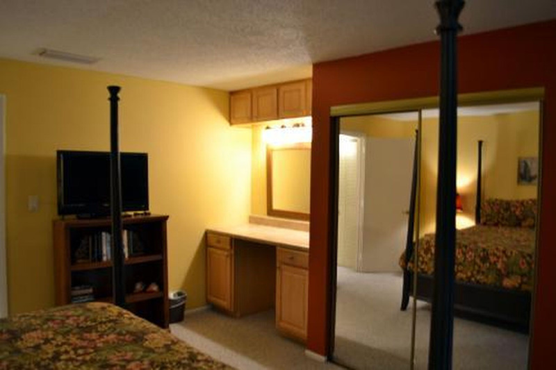 room with bed, TV, countertop, and glass doors for the closet