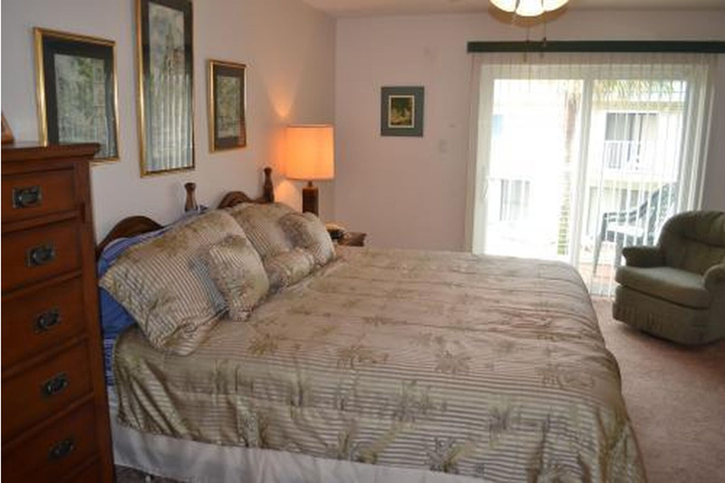 gold sheeted king size bed with dresser next to it and glass sliding doors