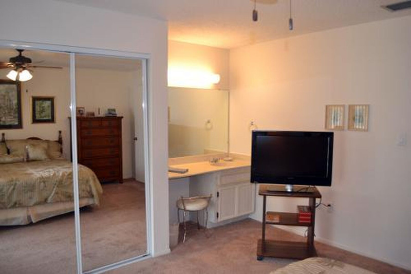 bedroom with a tv, countertop, and mirror closet facing the bed