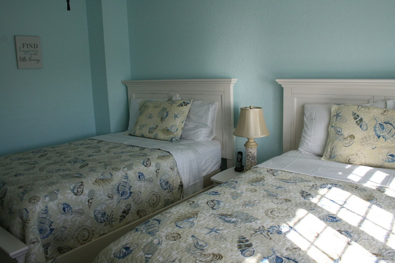 two full size mattresses separated by a lamp and table between them
