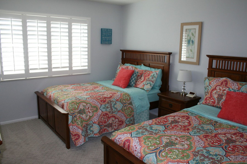 two full size mattresses separated by a lamp and table between them