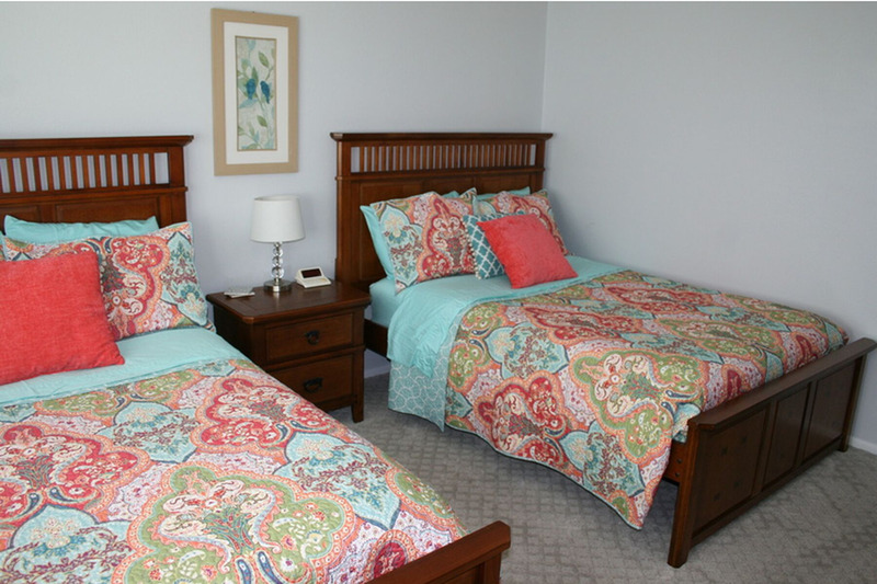 two full size mattresses separated by a lamp and table between them