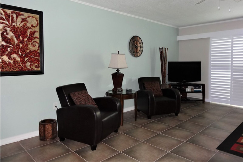 living room with paintings, a clock, and two chairs