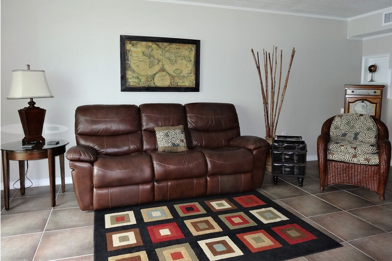 living room with large brown couch and a square decorated rug