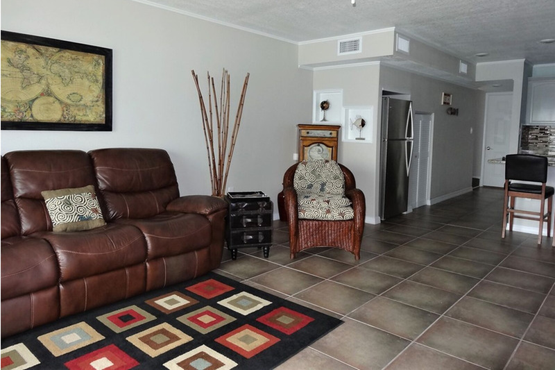 living room with paintings, a clock, and two chairs