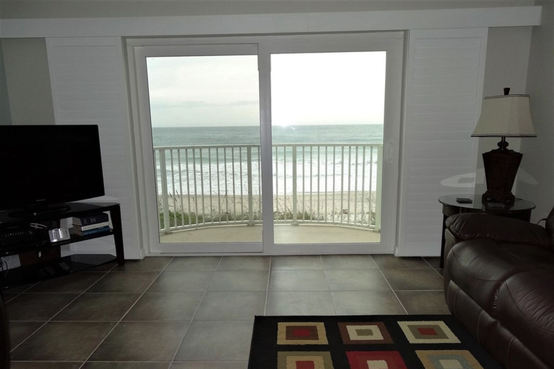 living room with a sliding glass door with the ocean behind it