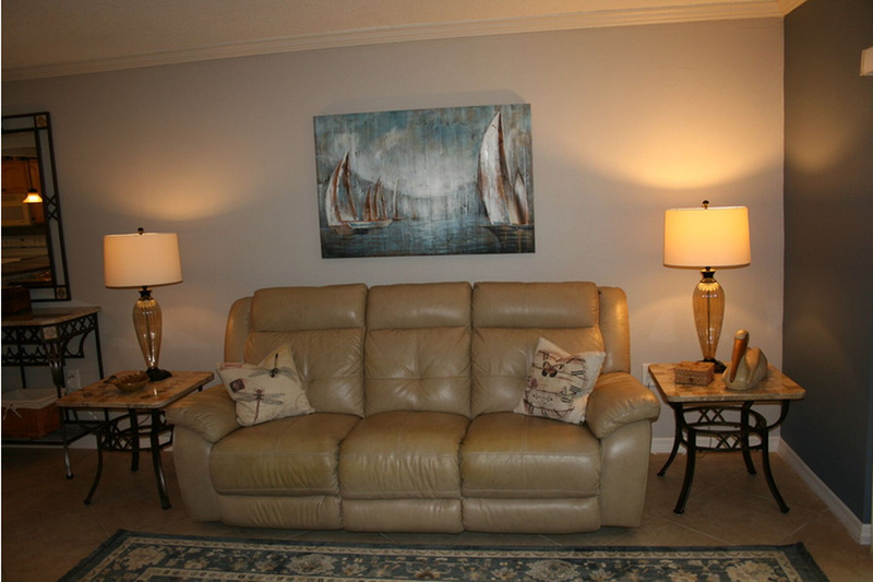 couch with a painting of ships at sea behind it and a lamp on either side