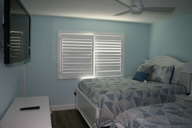 two blue beds in a spare bedroom facing a tv