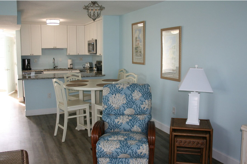 white dining table with a blue kitchen behind it