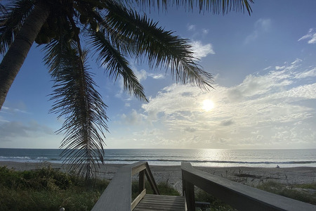 picture of the ocean from a boardwalk going towards the sand