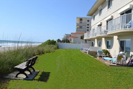 oceanfront Villas by ocean edge with bench on green grass