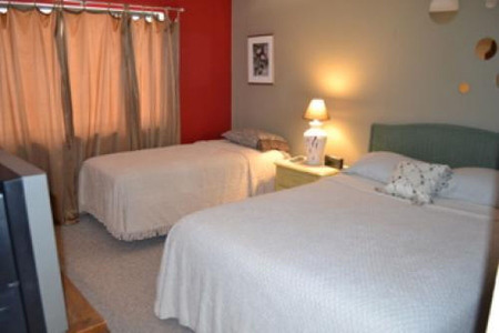two full size mattresses separated by a lamp and table between them