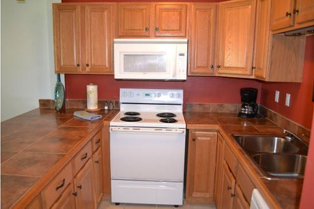 view of the sink, stove, kitchen cabinets and counter-top all an orange-red color
