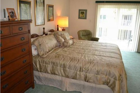 gold sheeted king size bed with dresser next to it and glass sliding doors