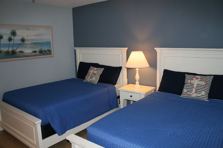 two blue sheeted beds with a lamp separating them