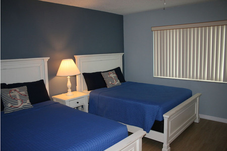 two blue sheeted beds with a lamp separating them