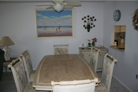 6 person beige dining table with decorative walls featuring a painting, clock, and a plant