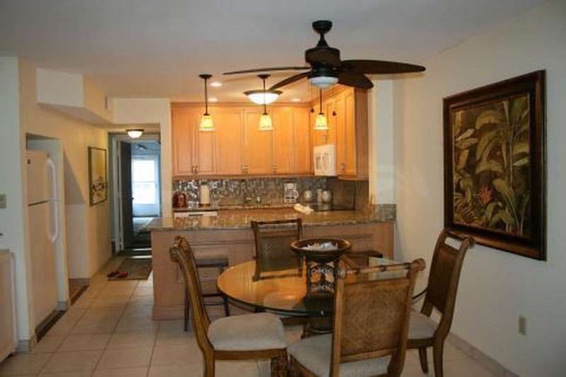well lit dining area with kitchen and dining table with glass table